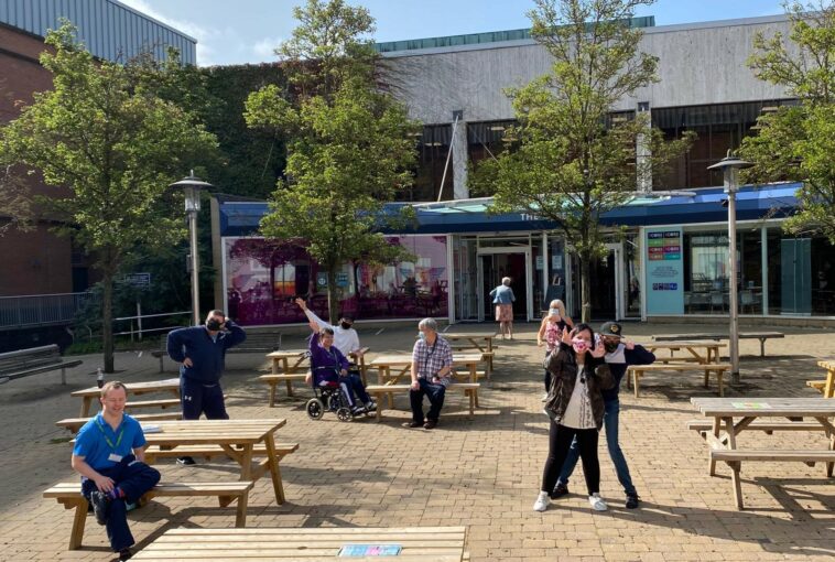 A group of people are outside enjoying the sunshine