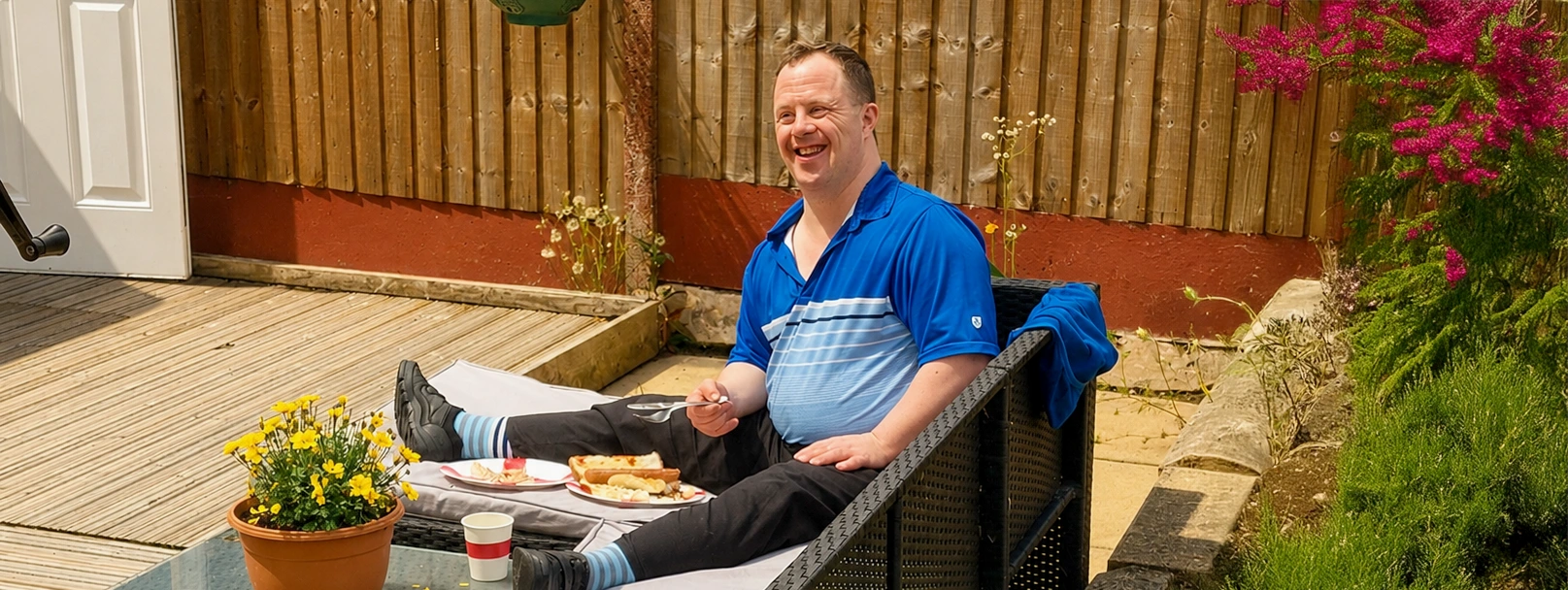 Man sitting in on garden sofa eating a BBQ meal