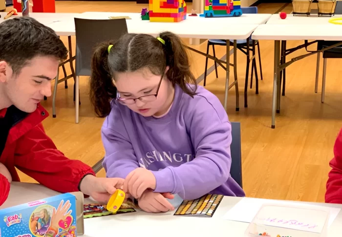 Support worker playing with a young service user at a table