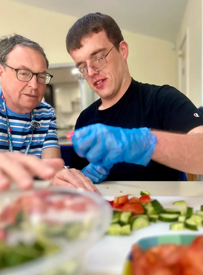 Volunteer helping a service user prepare food at SoLO