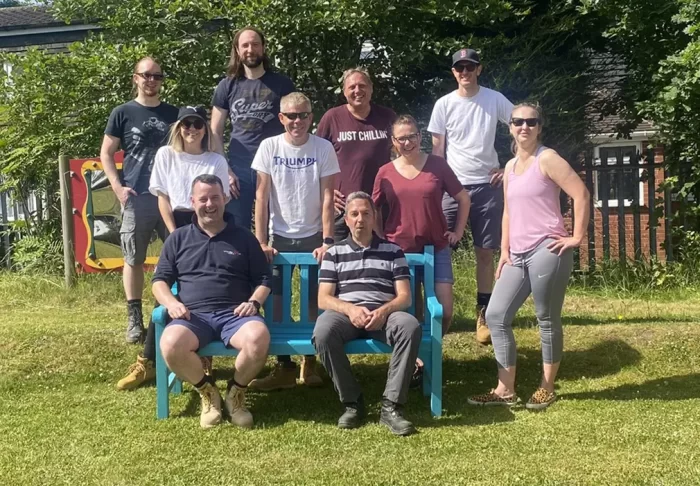 Group of volunteers sitting and standing around a garden bench