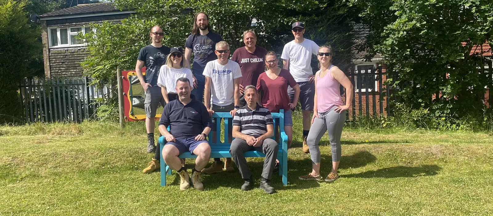 Group of volunteers sitting and standing around a garden bench